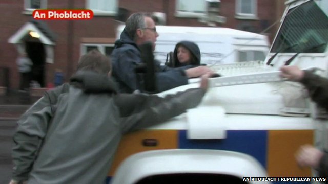 Gerry Kelly hangs on to front of police vehicle