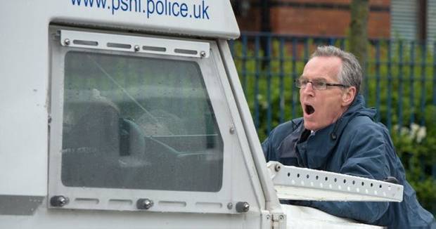 Sinn Fein Gerry Kelly being carried by a police jeep
